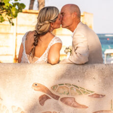 A newly married couple shares a private moment and a kiss together on one of the concrete benches along the shoreline in Puerto Morelos.