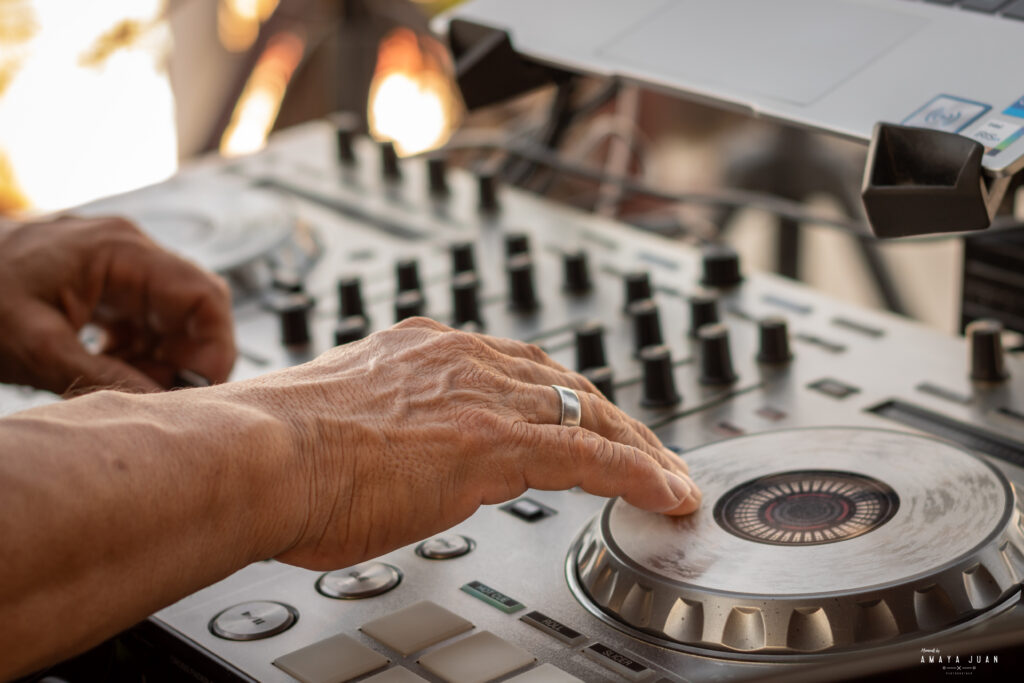 A wedding DJ mixes music for a wedding reception on the rooftop at La Sirena Puerto Morelos overlooking the sea.