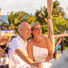 The newlyweds sit together for their first meal as a married couple on the rooftop of La Sirena Puerto Morelos. A guest in the foreground holds a Mexican margarita glass in his hand.