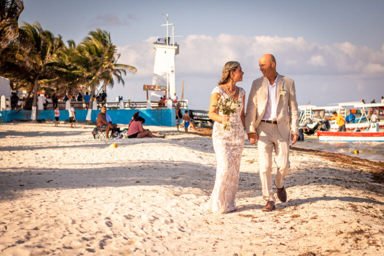 A newly married couple walk on the busy beach in Puerto Morelos, surrounded by other beachgoers and fisherman - the quintessential Puerto Morelos experience.