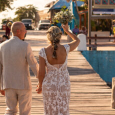 A newlywed couple celebrates their new marriage, walking hand-in-hand down the pier in Puerto Morelos.