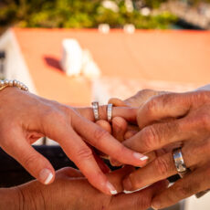 The groom places the bride's wedding ring on her finger during their wedding ceremony.