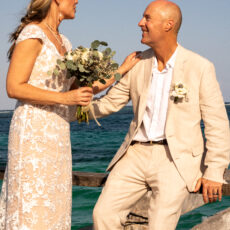 Bride and groom posing for wedding photos taken by local photographer Moments by Amaya Juan on the pier in Puerto Morelos.