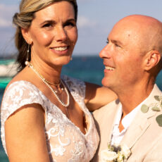 Beautiful bride looking at the camera and her groom gazing lovingly at her.