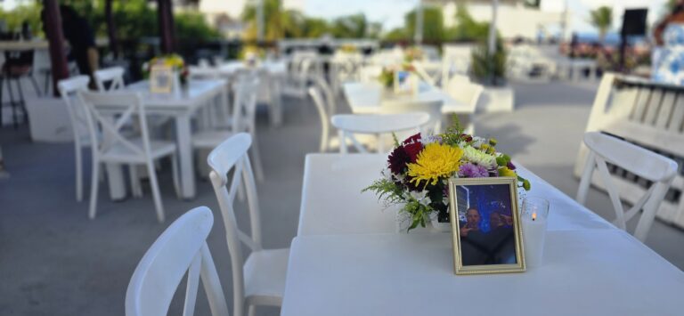 Wedding reception table with a flower centerpiece and framed photo on a rooftop in Puerto Morelos